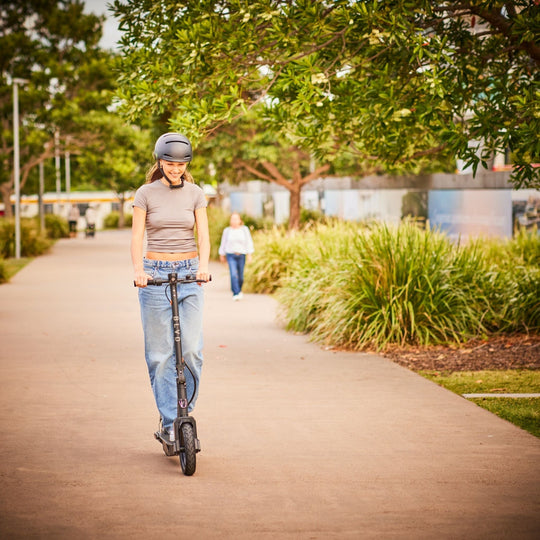 young lady with helmet riding a blvd elite electric scooter on pathway