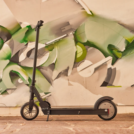 blvd forge electric scooter standing stationary in front of graffiti art