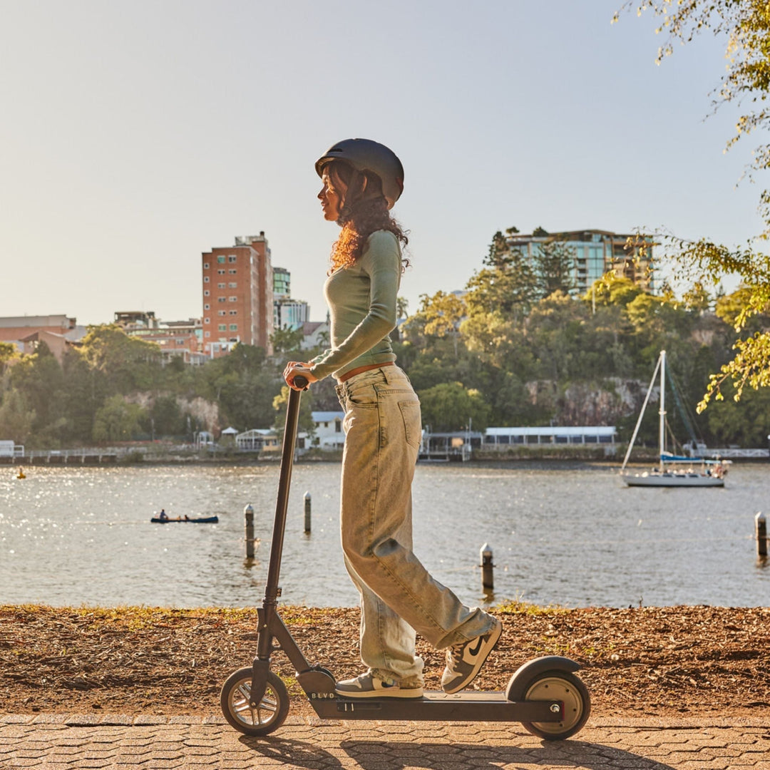lady riding a blvd forge electric scooter along riverbank