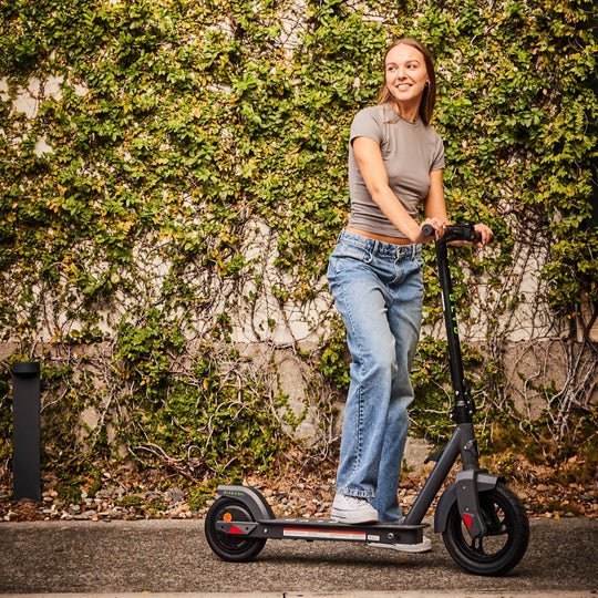 lady smiling on a blvd urbn plus electric scooter in front of garden wall