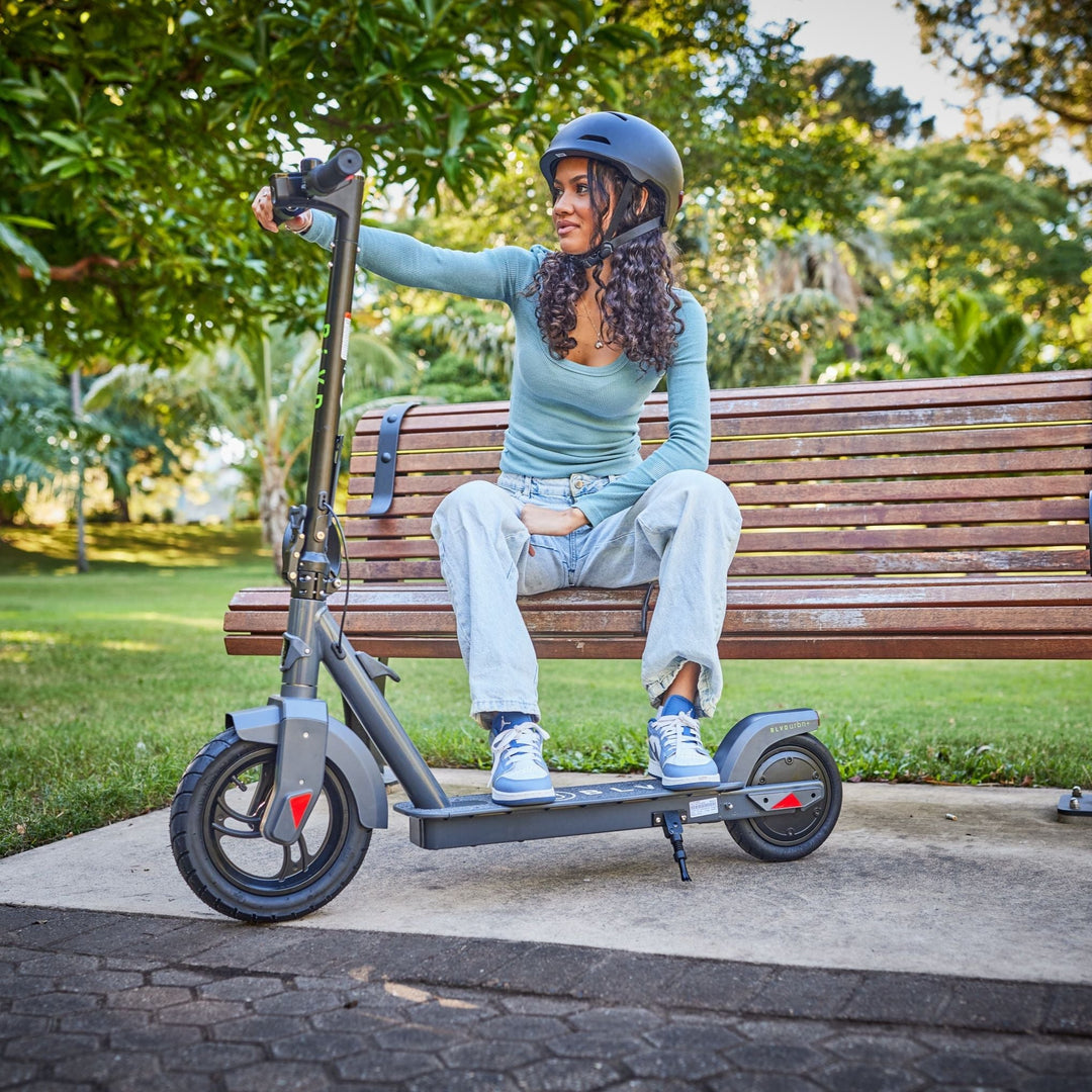 young adult female resting on a park bench with her blvd urban plus electric scooter