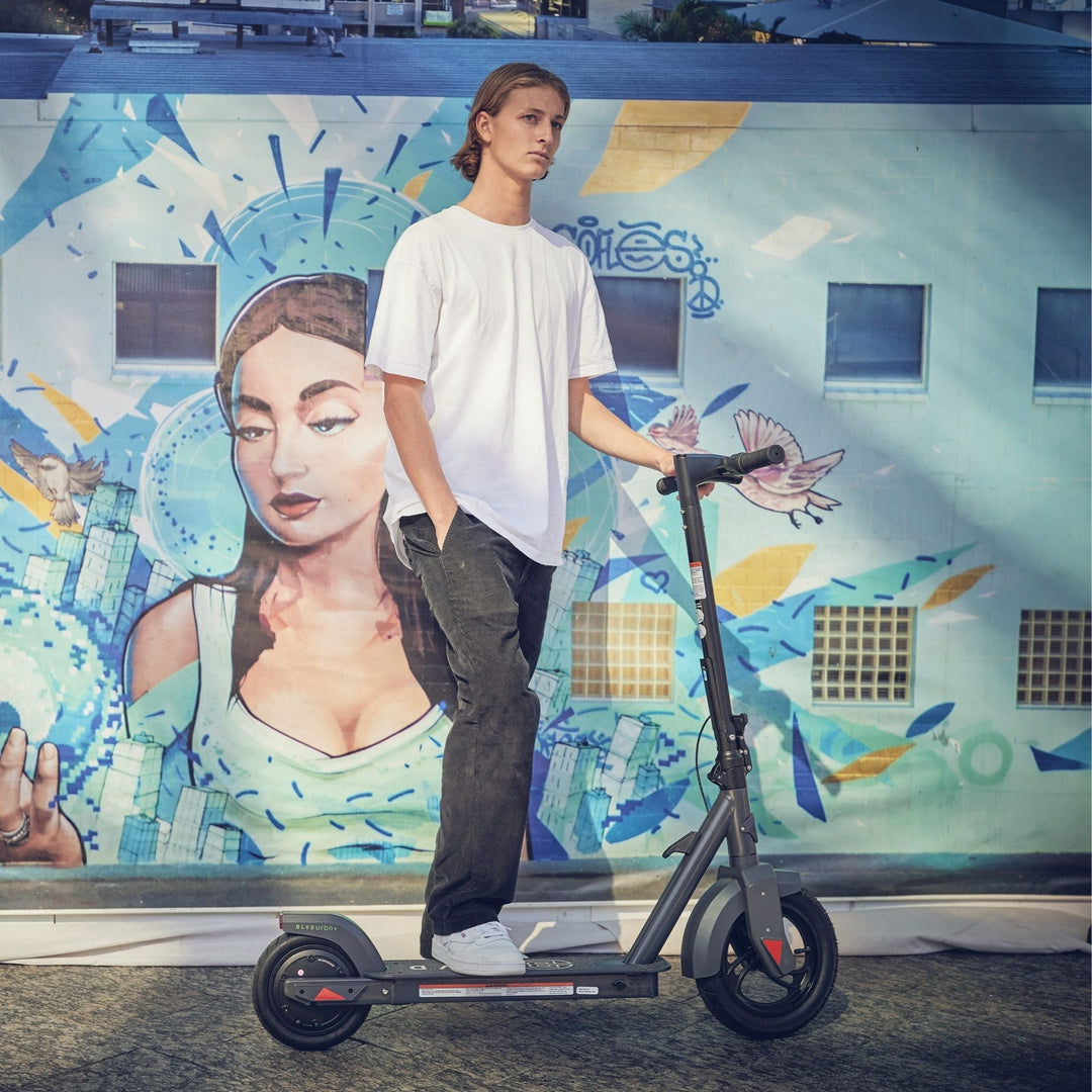 man standing with his blvd urbn plus electric scooter in front of street art